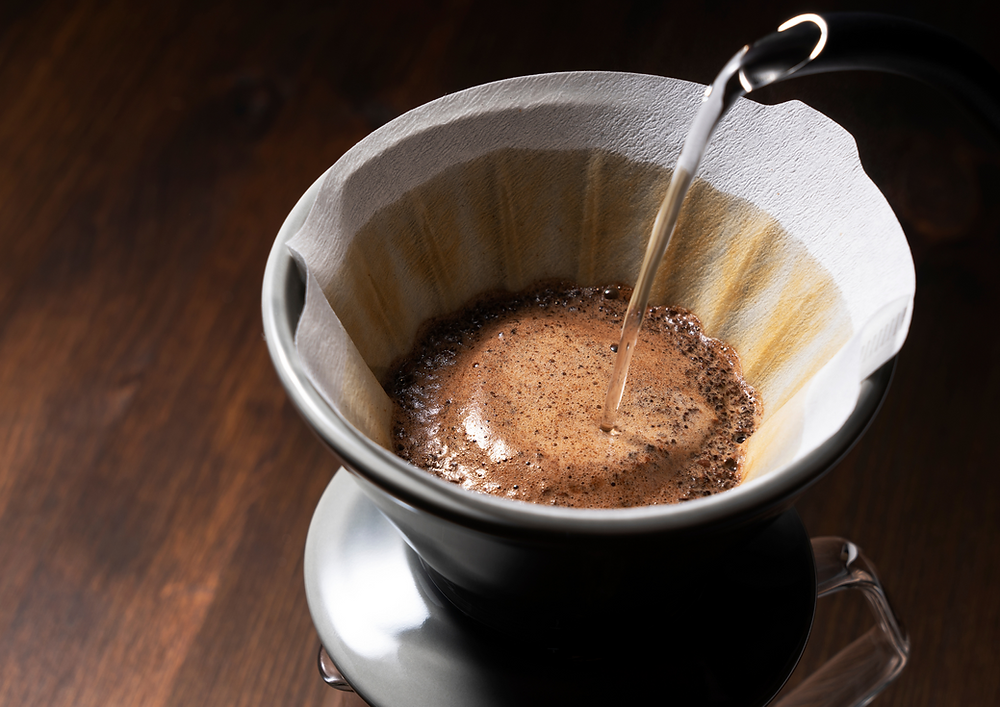Pouring hot water over coffee grounds in filter.